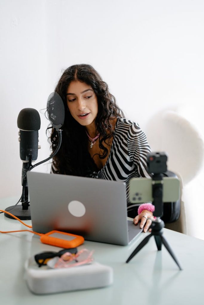 pexels photo 13929964 A young woman using a microphone and laptop to record a podcast indoors, showcasing a modern content creation setup.
